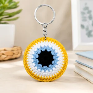 Handmade evil eye crochet keychain with yellow border and blue nazar design on table