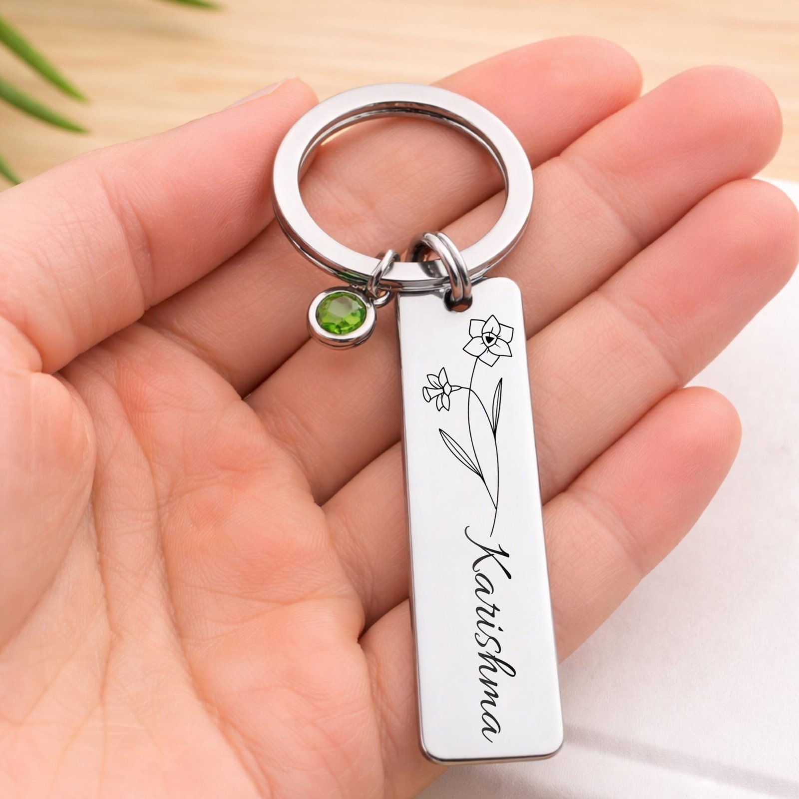 Personalized birth flower name keychain with green birthstone charm held in hand showing real size metal keyring