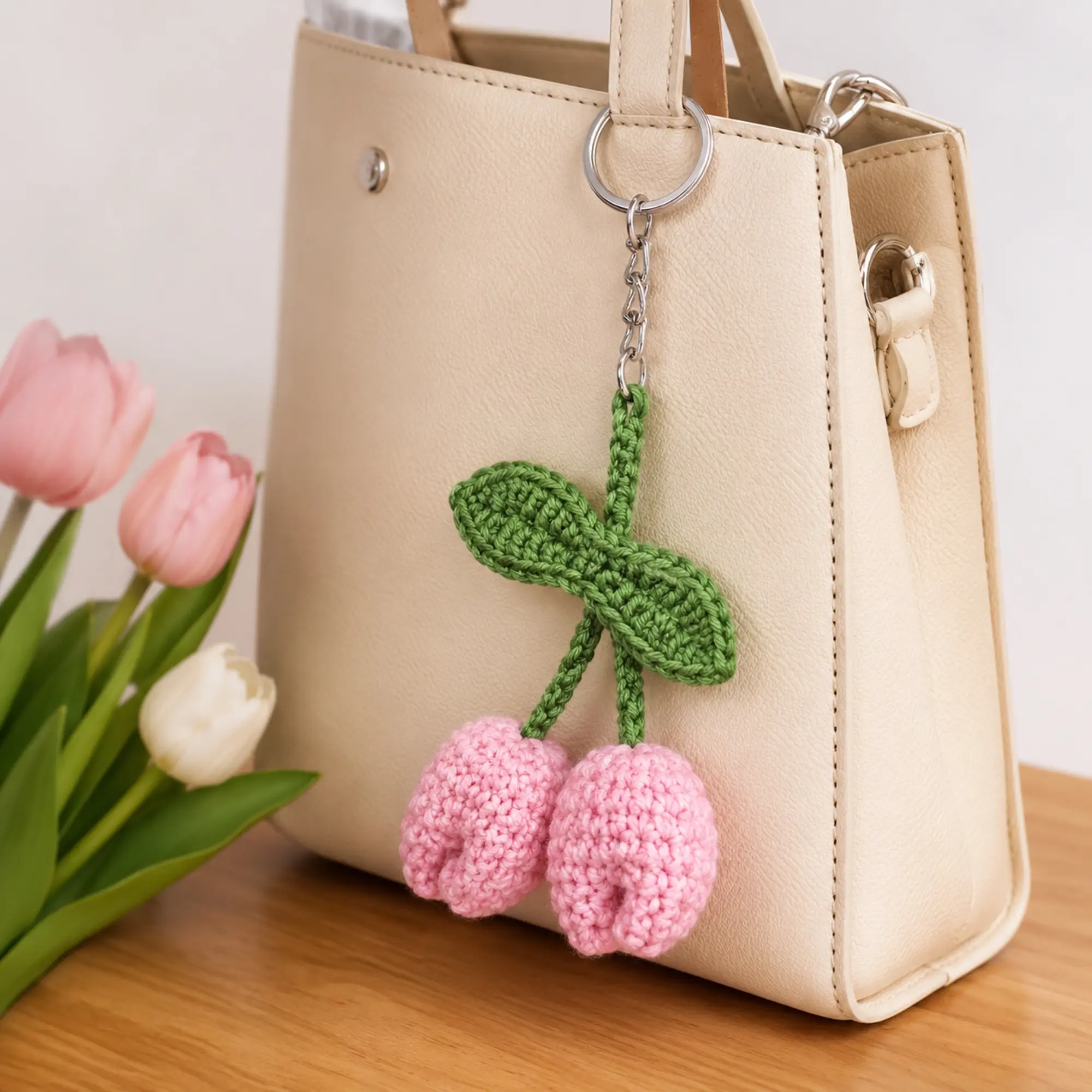 Handmade crochet tulip keychain attached to a beige handbag as a decorative bag charm accessory