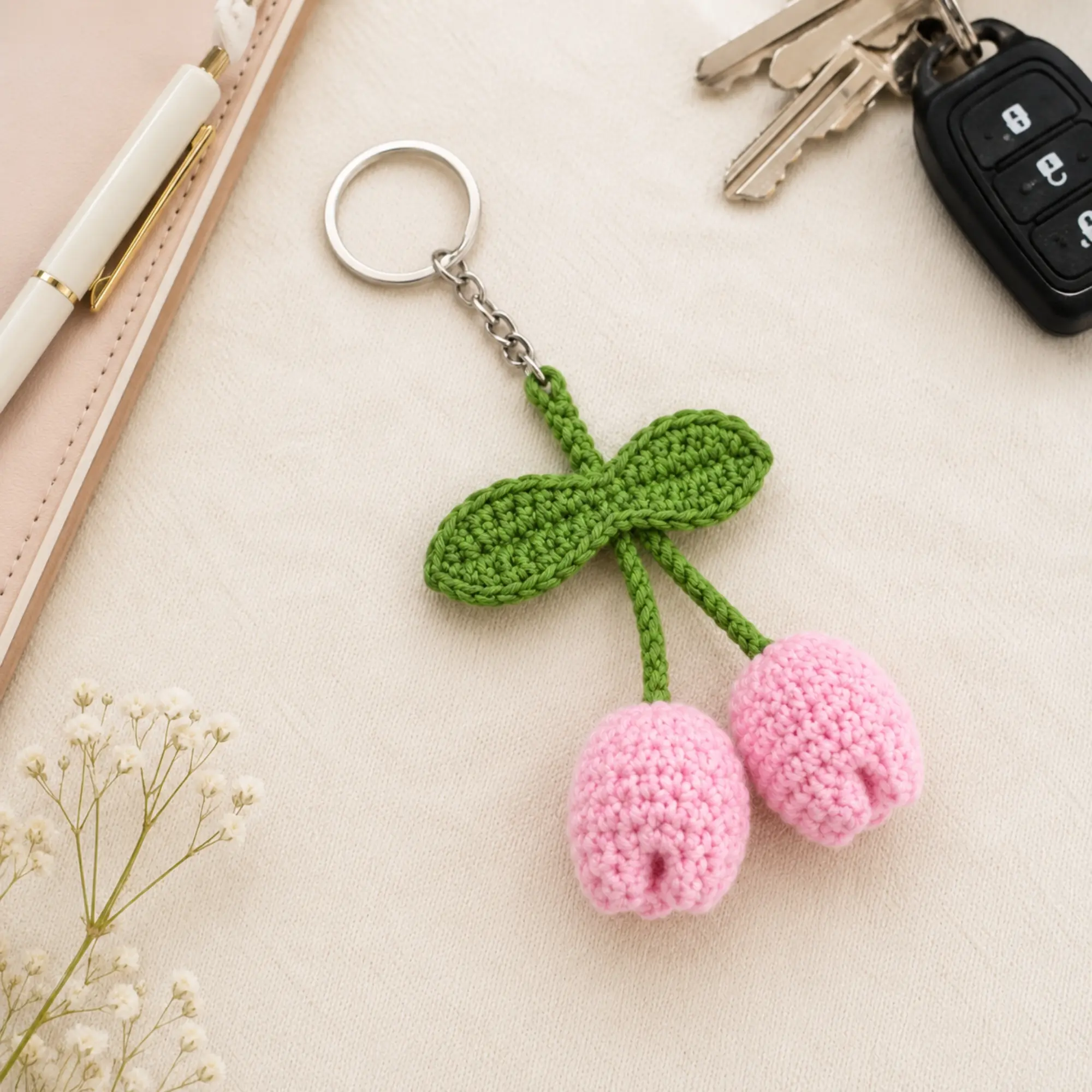 Handmade crochet tulip keychain placed with keys, car key, notebook and pen showing everyday use as a stylish accessory