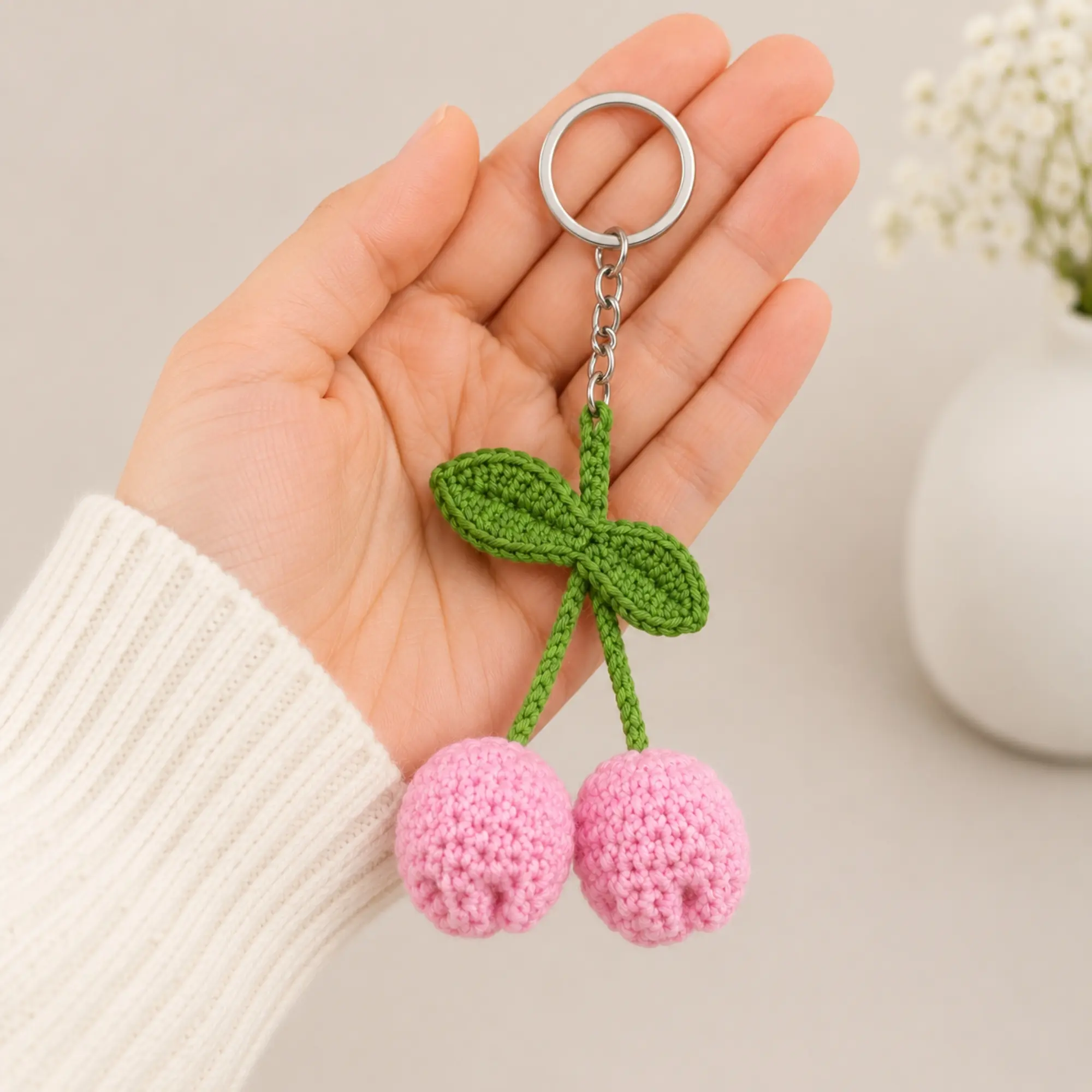 Handmade crochet tulip keychain shown in hand for size reference with pink tulip flowers and green leaves
