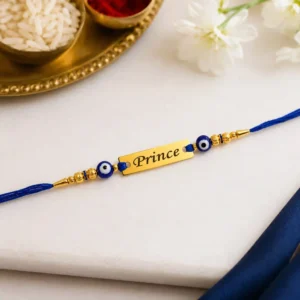 Close-up of a personalized Evil Eye Name Rakhi with a custom gold name plate, blue thread, and premium gold finish beads for Raksha Bandhan.