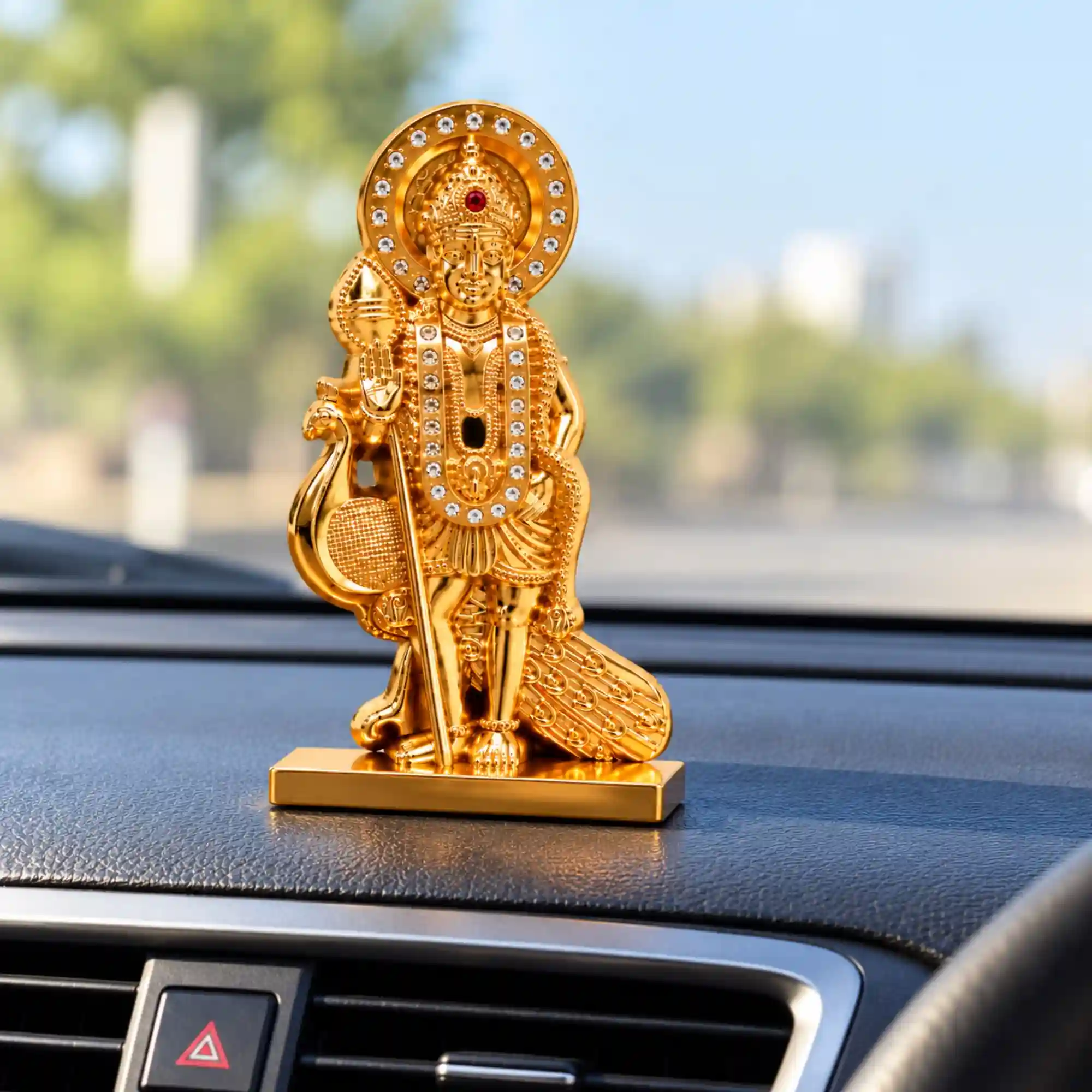 Lord Murugan idol with golden finish displayed on car dashboard