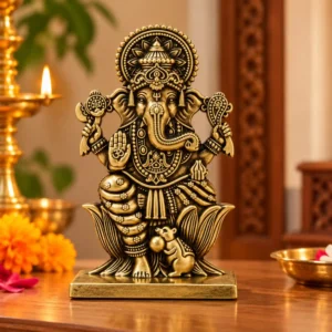 Antique Brass Finish Ganesh Idol made from white metal, featuring an ornate crown, lotus base and mouse figure in a home pooja setting.