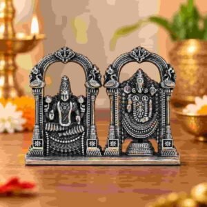Antique silver Tirupati Balaji idol displayed on a wooden surface in a festive puja setting with glowing diyas.
