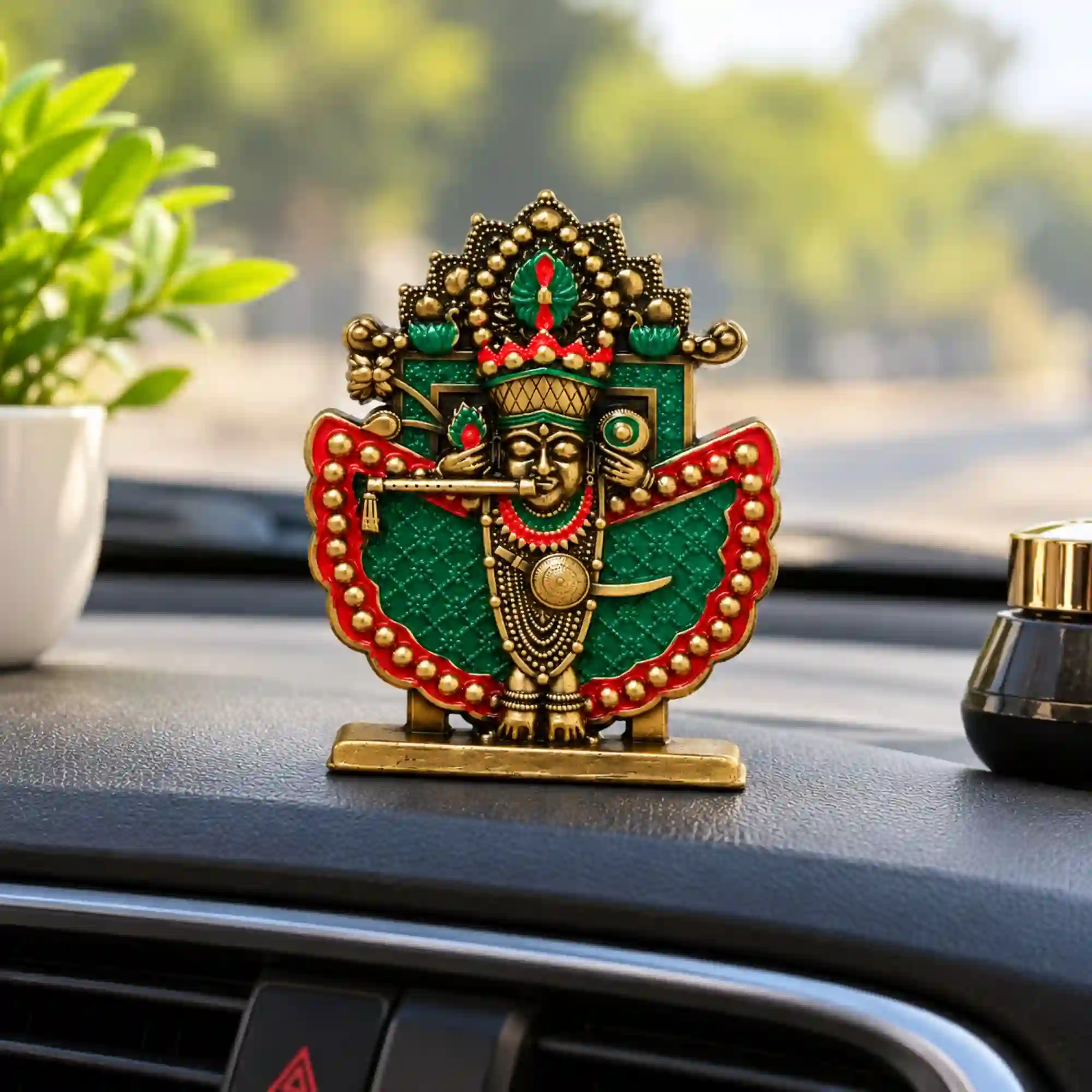 Shri Sanwaliya Seth idol with antique brass finish, green and red detailing, displayed on a car dashboard