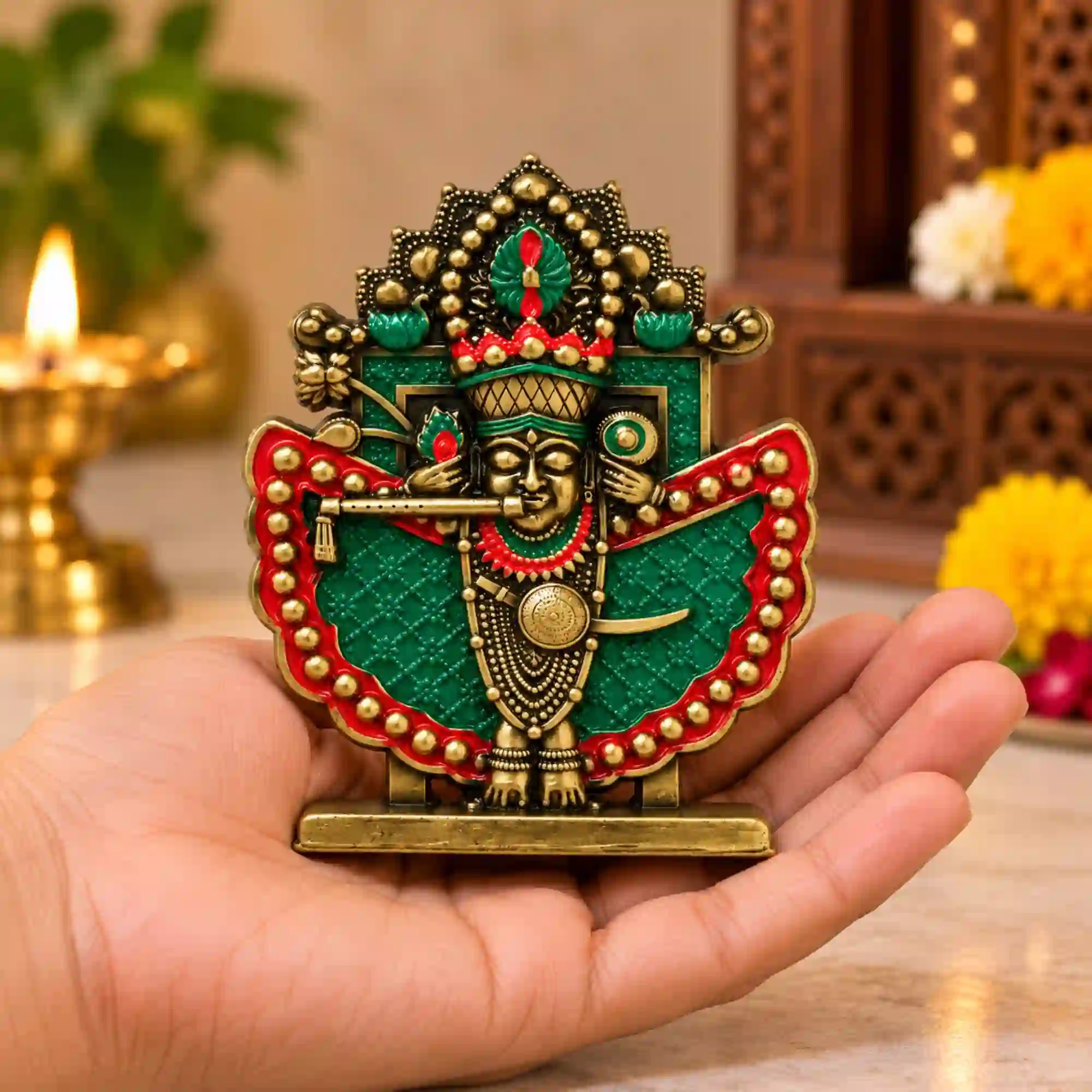 Small Shri Sanwaliya Seth idol in antique brass finish held in an open palm, showing its compact size and green-red decorative details
